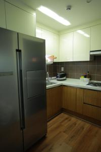 a kitchen with a stainless steel refrigerator and wooden cabinets at Sunyhouse Female Only Foreign Only in Seoul +12 photos