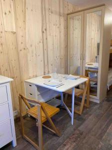 Zimmer mit einem Tisch, Stühlen und Holzwänden in der Unterkunft Studio refait à neuf avec balcon - Famille - Parking couvert in Chamrousse