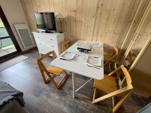 a room with a white table and chairs and a tv at Studio refait à neuf avec balcon - Famille - Parking couvert in Chamrousse