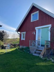 una casa roja con porche y puerta en Gästhus i Slöinge nära Skrea strand en Slöinge
