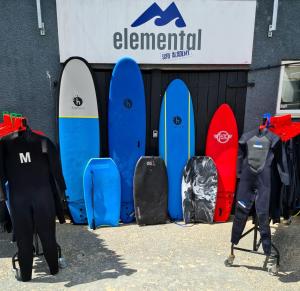 a group of surfboards are lined up against a wall at Elemental Surf Lodge in Newquay