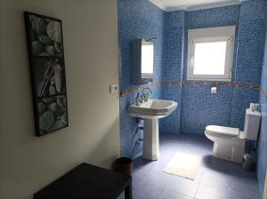 baño de azulejos azules con lavabo y aseo en La Cariñosa en Naveces