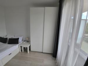 a white bedroom with a bed and a window at SDP Meder B401 Apartment in Budapest