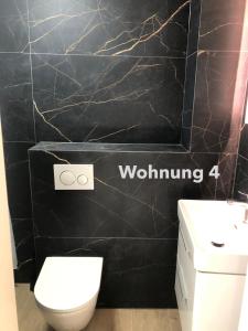 a bathroom with a white toilet and a black wall at Zentrale Innenstadt-Wohnung in Würzburg
