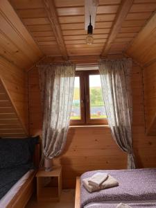 a bedroom in a log cabin with a bed and a window at Cabanówka in Hoczew