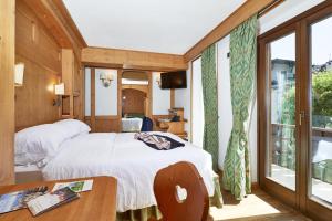 a bedroom with a bed and a large window at Hotel Garni dello Sportivo in Madonna di Campiglio