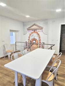a white table and chairs in a room with a mural at Apartamentos Plaza Santo Domingo in Cádiz