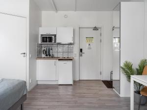 una cocina con electrodomésticos blancos y una habitación con cama en Part-Time Home Slagsta Strand, en Norsborg