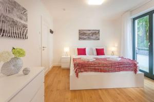 ein weißes Schlafzimmer mit einem großen Bett mit roten Kissen in der Unterkunft Villa Friede-Marie App Freya in Sassnitz