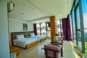 a hotel room with two beds and a balcony at Happy Light Hotel Nha Trang in Nha Trang