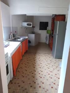 a kitchen with orange cabinets and a tile floor at Maison La voûte plage à 50m et rivière à proximité in Vieux-Habitants