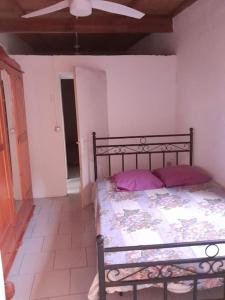 1 dormitorio con cama con almohadas moradas y techo en Maison La voûte plage à 50m et rivière à proximité, en Vieux-Habitants