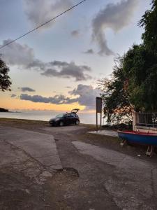 un coche aparcado al lado de una carretera con un barco en Maison La voûte plage à 50m et rivière à proximité, en Vieux-Habitants 8 fotos más