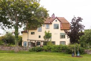 uma grande casa branca com uma parede de pedra em Villa Wäring Husrum & Frukost em Varberg