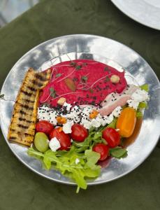 ein Teller mit Fleisch und Gemüse auf dem Tisch in der Unterkunft Hotel უცხო-utskho in Telawi