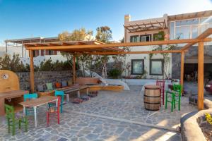フィロステファニにあるOlive Leaf Housesのカラフルな椅子とテーブル付きのパティオ、建物