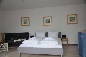 een slaapkamer met een bed met witte lakens en een bank bij Villa Monika App 7 in Sassnitz