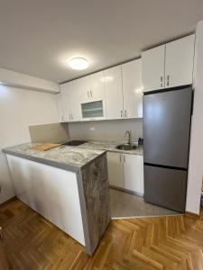 a kitchen with white cabinets and a stainless steel refrigerator at Apartman 24 in Ledine