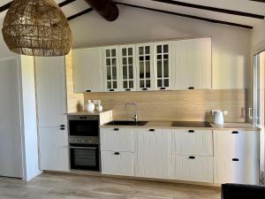 uma cozinha com armários brancos e um lavatório em Mini Villa St-Lucie Porto-Vecchio vue mer 5mnplage em Zonza
