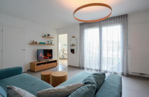 a living room with a blue couch and a tv at Le Bleu Du Lac 3 étoiles - Secteur recherché, Calme & familiale, à 300m du lac & de la vieille ville, Garage privé in Annecy