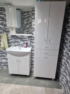 a bathroom with a sink and a white cabinet at Apartmani kod Kmeta in Janja