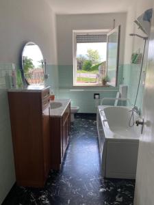 een badkamer met een bad, een toilet, een wastafel en een spiegel bij Appartamento " Le Farfalle " in Santorso