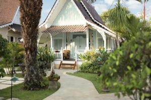 une maison blanche avec une terrasse couverte dotée d'un banc dans l'établissement Puri Tempo Doeloe Boutique Hotel, à anur