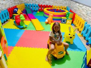 une petite fille assise sur une voiture de jouets dans une salle de jeux dans l'établissement Impero Hotel Beauty & Spa - Bike Hotel, à Cantello