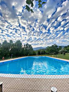 a large blue swimming pool with a cloudy sky at Complejo Godoy in Losar de la Vera
