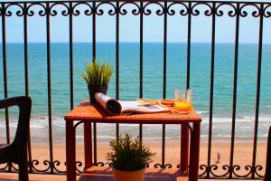a table with a glass of orange juice on the beach at Sea You Apartamentos Valencia Port Saplaya in Port Saplaya