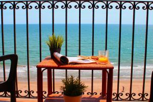 una mesa con un vaso de zumo de naranja en la playa en Sea You Apartamentos Valencia Port Saplaya, en Port Saplaya