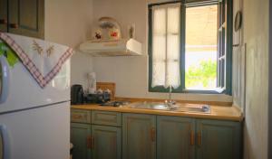 a kitchen with a sink and a white refrigerator at Koralia Apartments in Kýthira
