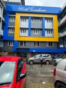 a man standing in front of a building with parked cars at Hotel Vrindavan in Wayanad
