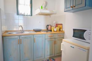 a kitchen with blue cabinets and a sink and a microwave at Koralia Apartments in Kythira