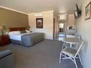 a bedroom with a bed and a table and chairs at The Saltbush Motor Inn in Hay
