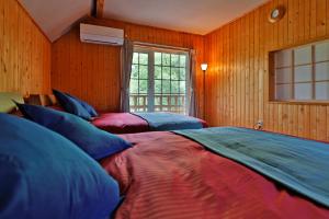 three beds in a room with wooden walls and a window at The LODGE ABASHIRI in Abashiri