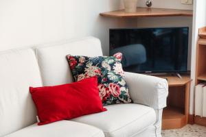 białą kanapę z czerwoną poduszką i telewizorem w obiekcie Mulino Nuovo by Quokka 360 - spacious apartment on the Swiss border w Como