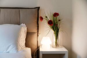 un vaso con fiori rossi su un tavolo accanto a un letto di Mulino Nuovo by Quokka 360 - spacious apartment on the Swiss border a Como