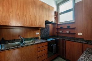a kitchen with wooden cabinets and a sink and a window at Mulino Nuovo by Quokka 360 - Spacious Apartment on the Swiss Border in Como