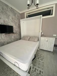 a white bed in a room with a tv at 1st line apartment in Kobuleti in K'obulet'i