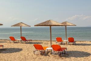 eine Gruppe von Stühlen und Sonnenschirmen am Strand in der Unterkunft Sun Beach Hotel in Agía Triás