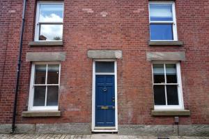 a brick building with a blue door and three windows at 4 Bedroom Town House in Macclesfield