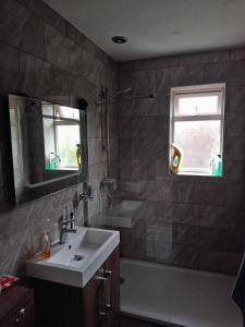 uma casa de banho com um lavatório e uma banheira em Cosy room with 3 bed spaces in a friendly bungalow em Bletchley
