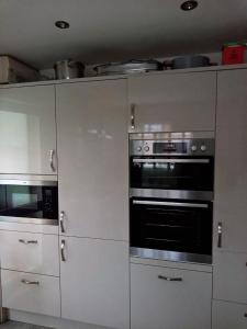 cocina con armarios blancos y horno en Cosy room with 3 bed spaces in a friendly bungalow en Bletchley