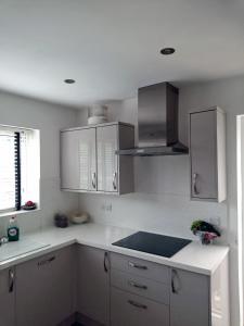 una cocina con encimeras blancas y armarios de acero inoxidable en Cosy room with 3 bed spaces in a friendly bungalow en Bletchley