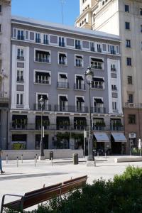 een groot gebouw met een bank ervoor bij Hotel Regina in Madrid
