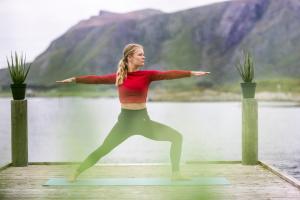 Eine Frau, die Yoga auf einem Dock in der Nähe eines Wasserkörpers macht. in der Unterkunft Hustadvika Havhotell - by Classic Norway Hotels in Farstad