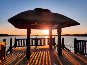 a gazebo on a dock with the sun setting at Cztery Pory Roku in Wiele
