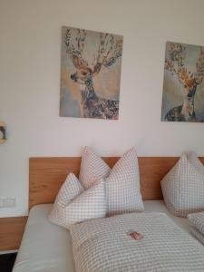 Schlafzimmer mit einem Bett mit Kissen und Gemälden an der Wand in der Unterkunft Valbella Appartements in Partenen