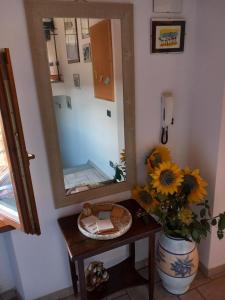 baño con espejo y jarrón de girasoles en casadipaola, en Gambassi Terme